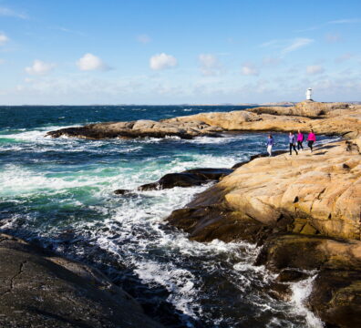 Grupp vandrar på Marstrandsön med hav i bild